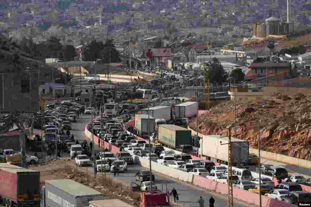People make their way as they attempt to cross into Lebanon at the Masnaa border crossing between the Lebanon and Syria, after Syrian rebels announced that they have ousted President Bashar al-Assad.