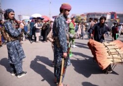Members of Taliban security forces stand guard among crowds of people walking past in a street in Kabul, Afghanistan, Sept. 4, 2021.