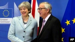 英国首相特蕾莎.梅（左）和欧洲委员会主席容克在布鲁塞尔谈判前握手