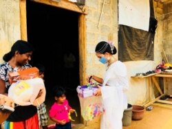 Pawani Rasanga hands a care package to a child in the small town of Malimbada, about 160 kilometers (99 miles) south of the capital Colombo.