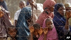 FILE - People queue outside a food distribution center as they wait to be registered as refugees in Dadaab, Kenya, Aug. 1, 2011. 