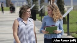 In this Friday, April 10, 2020 photo, Ebru Ural, left, and her daughter Serra Sowers take a walk to discuss choosing colleges without actually visiting them at a park in Sanford, Florida. (AP Photo/John Raoux)
