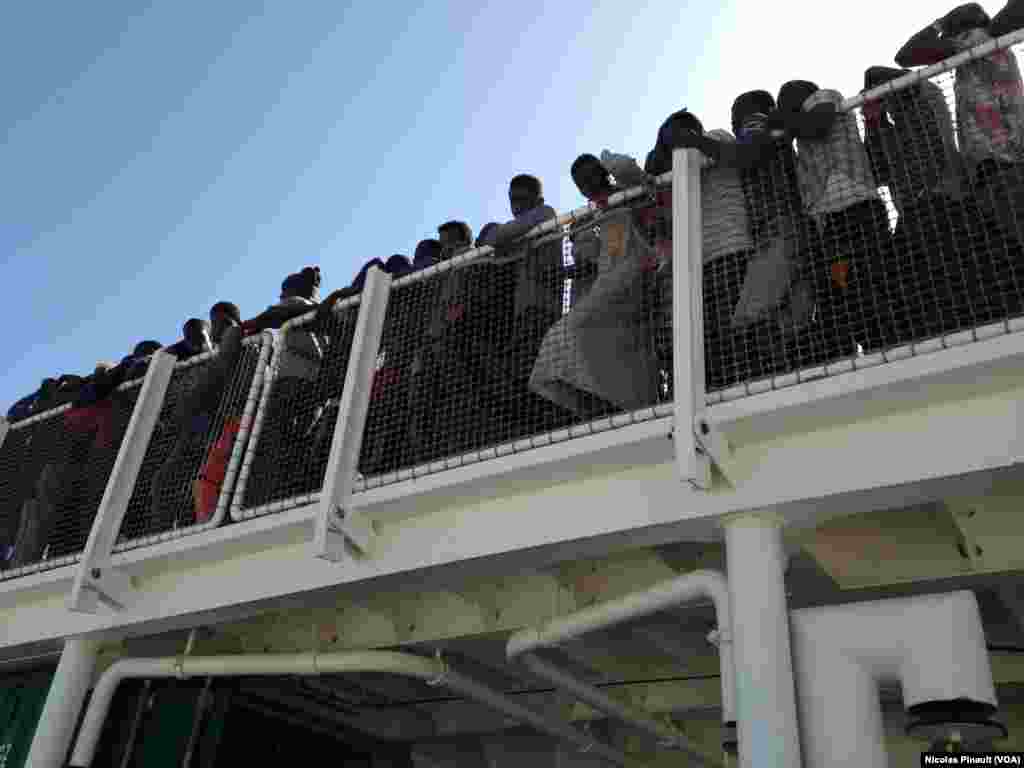Sous le soleil de Sicile, plus de 500 migrants attendent de debarquer du navire espagnol &quot;Rio Segura&quot;, Pozzallo, Sicile, 7 octobre 2015 (Nicolas Pinault/VOA).