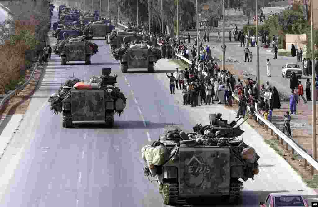 Iraqis cheer a column of U.S. armored vehicles arriving in Bagdhad, April 10, 2003. 