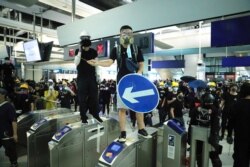 FILE - Demonstrators stand on turnstiles during a protest at the Yuen Long MTR station in Hong Kong, August 21, 2019.
