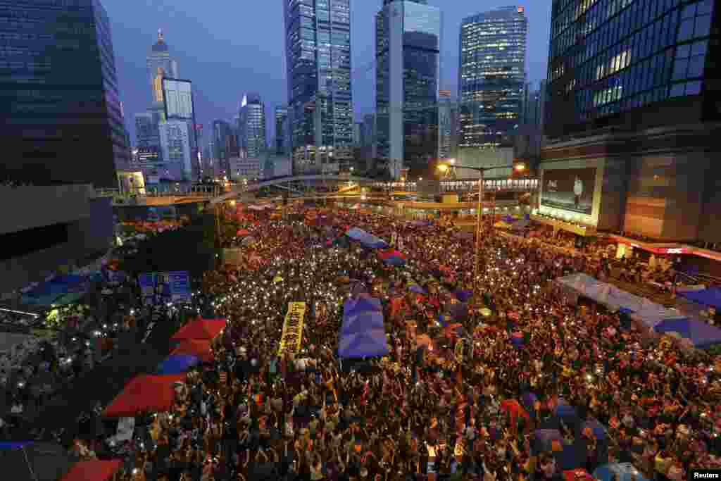 Para demonstran pro-demokrasi memegang spanduk dan menyalakan lampu dari ponsel mereka dalam peringatan satu bulan protes, di distrik keuangan Hong Kong (28/10).&nbsp;(Reuters/Damir Sagolj) 