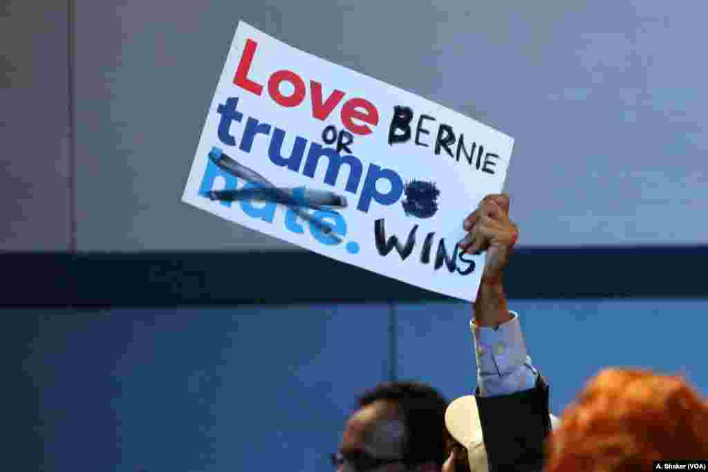 A Bernie Sanders supporter holds a modified Hillary Clinton campaign sign at the Democratic National Convention in Philadelphia, July 25, 2016. (A. Shaker/VOA)