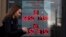 FILE - A woman walks past a currency exchange office display listing the exchange rates of U.S. dollar and euro to Russian rubles, in Moscow, Russia, March 9, 2020. 