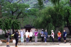 Visitors wearing face masks to help protect against the spread of the coronavirus pose to take pictures at the Gyeongbok Palace in Seoul, South Korea, Aug. 17, 2020.