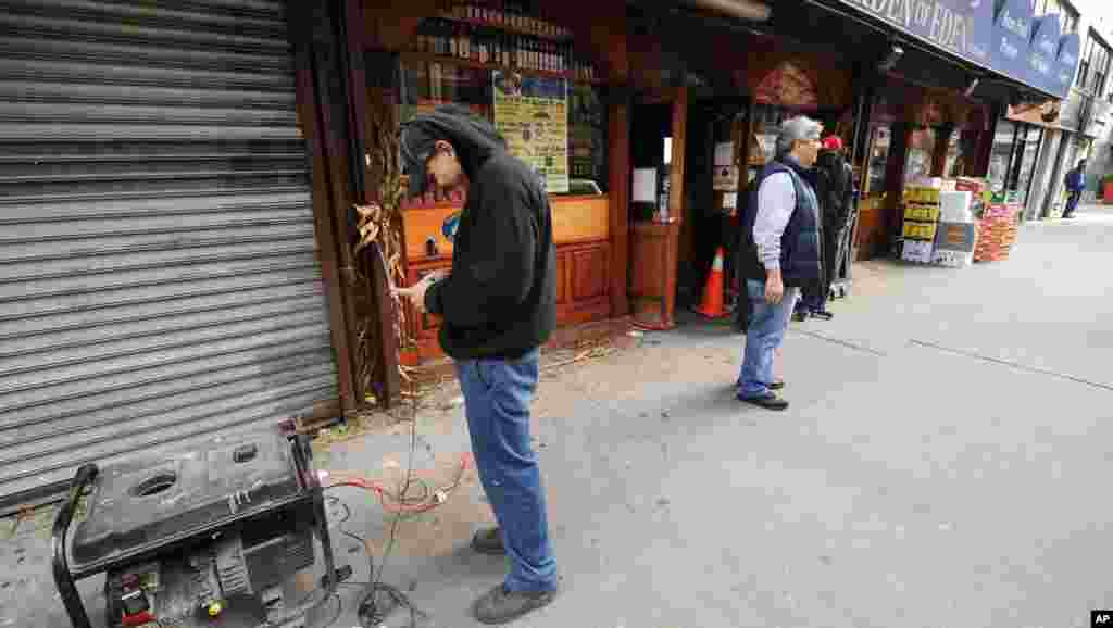 A New York resident charges his cell phones from a generator connected to a 14th street market in the still powerless Chelsea section of Manhattan, New York, November 1, 2012.