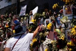 A woman mourns at a memorial site created by neighbors in front of a partially collapsed residential building as the emergency crews continue the search and rescue operations for survivors, in Surfside, Fla., July 3, 2021.