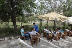 FILE - A waiter serves a group of people in a restaurant of Plaka district, as restaurants and cafes in Greece open after six months of lockdown, amid the coronavirus outbreak, in Athens, Greece, May 3, 2021.