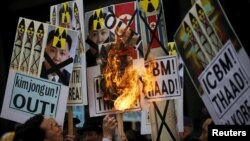 A man burns banners being held by protesters during an anti-North Korea rally in central Seoul, South Korea, Feb. 11, 2016.