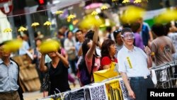 People take pictures behind a cutout of Chinese President Xi Jinping on which pro-democracy protesters put goggles and a yellow ribbon, their symbols, in the part of Mongkok shopping district protesters are occupying in Hong Kong, Oct. 31, 2014.