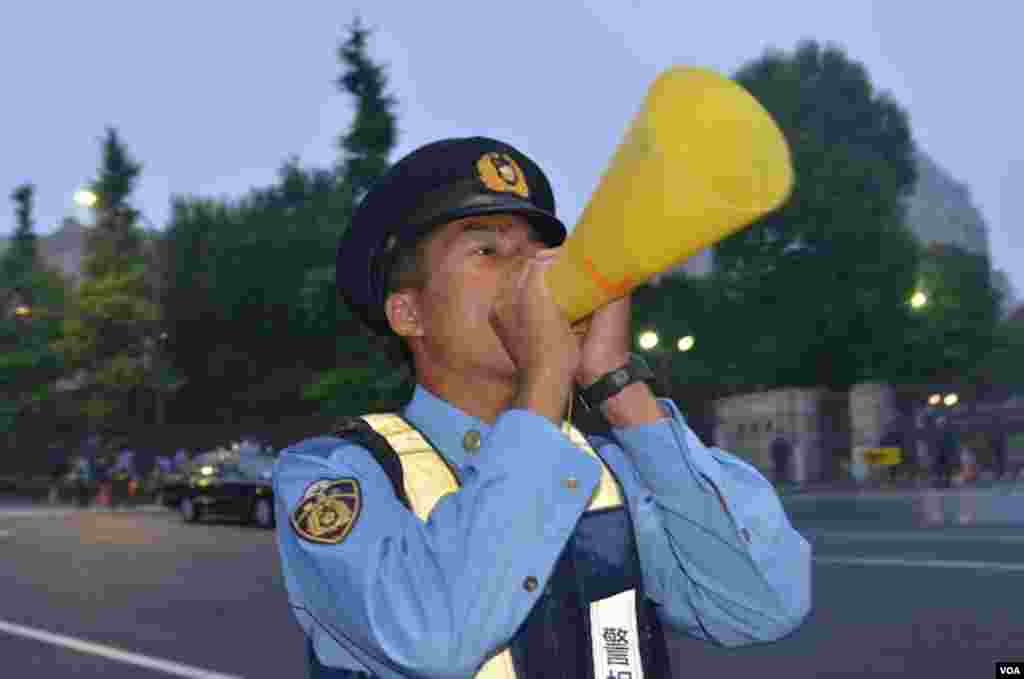 A Japanese police office keeps order at the protest against restarting nuclear power plants, Tokyo, Japan, July, 6, 2012. (S.L. Herman/VOA)