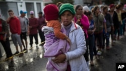 Maria del Carmen Mejia holds her daughter Britany Sofia while standing a line outside a migrant shelter in Tijuana, Mexico, Thursday, Nov. 22, 2018. 