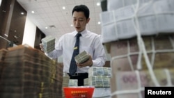一家银行职员2012年4月6日在河内外贸银行总部摆放一叠一叠的越南盾现钞