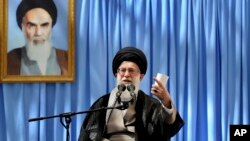 Iranian supreme leader's office, Supreme Leader Ayatollah Ali Khamenei delivers a speech in a ceremony marking the anniversary of the death of the late revolutionary founder Ayatollah Khomeini, shown in the picture at background, June 4, 2013.