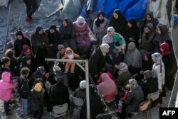 Palestinians sit amid tents and makeshift shelters that were destroyed in Israeli strikes in Deir el-Balah in central Gaza on March 2, 2024.