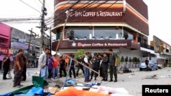 Para petugas tengah menginspeksi lokasi serangan bom di depan kedai kopi dan restoran Big Ben di propinsi Pattani (17/2). Dua orang relawan dilaporkan tewas dan 11 lainnya terluka dalam insiden ini.