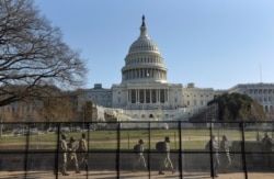 National Guard members walk behind a fence installed in front of the U.S. Capitol, a day after supporters of U.S. President Donald Trump occupied the Capitol building, in Washington, U.S., Jan. 7, 2021.
