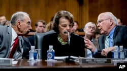 Senate Judiciary Committee Chairman Chuck Grassley, R-Iowa, left, accompanied by Sen. Dianne Feinstein, D-Calif., the ranking member, center, speaks with Sen. Patrick Leahy, D-Vt., right, during a Senate Judiciary Committee markup meeting on Capitol Hill,