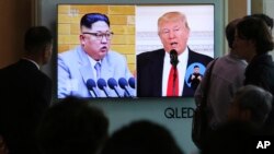 People watch a TV screen showing file footage of U.S. President Donald Trump, right, and North Korean leader Kim Jong Un during a news program at the Seoul Railway Station in Seoul, South Korea, April 21, 2018. 