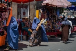 Burqa-clad women shop at a market in Kabul, Aghanistan, Aug. 23, 2021, following the Taliban's takeover of the country.