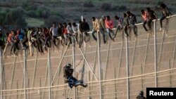 Un officier de la Garde civile espagnole tente d’empêcher un migrant africain de franchir une clôture frontalière entre le Maroc et l'enclave espagnole de Melilla, le 15 octobre 2014.