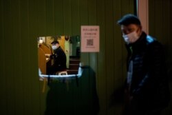 A man wearing a face mask walks past a barricaded residential compound in Wuhan, in China's central Hubei province, April 13, 2020.