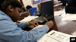 FILE - A student at Roosevelt High School fills out a college enrollment application at her school in Washington, D.C., Nov. 14, 2013.