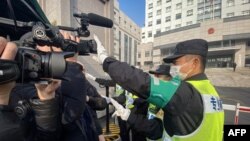 一名警察挡住记者的镜头阻止拍摄审讯公民记者张展的上海浦东新区法院外景。（2021年12月28日）