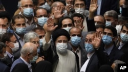 President Ebrahim Raisi, center, waves to journalists as he is surrounded by group of lawmakers after taking his oath as president at the parliament in Tehran, Iran, Aug. 5, 2021.