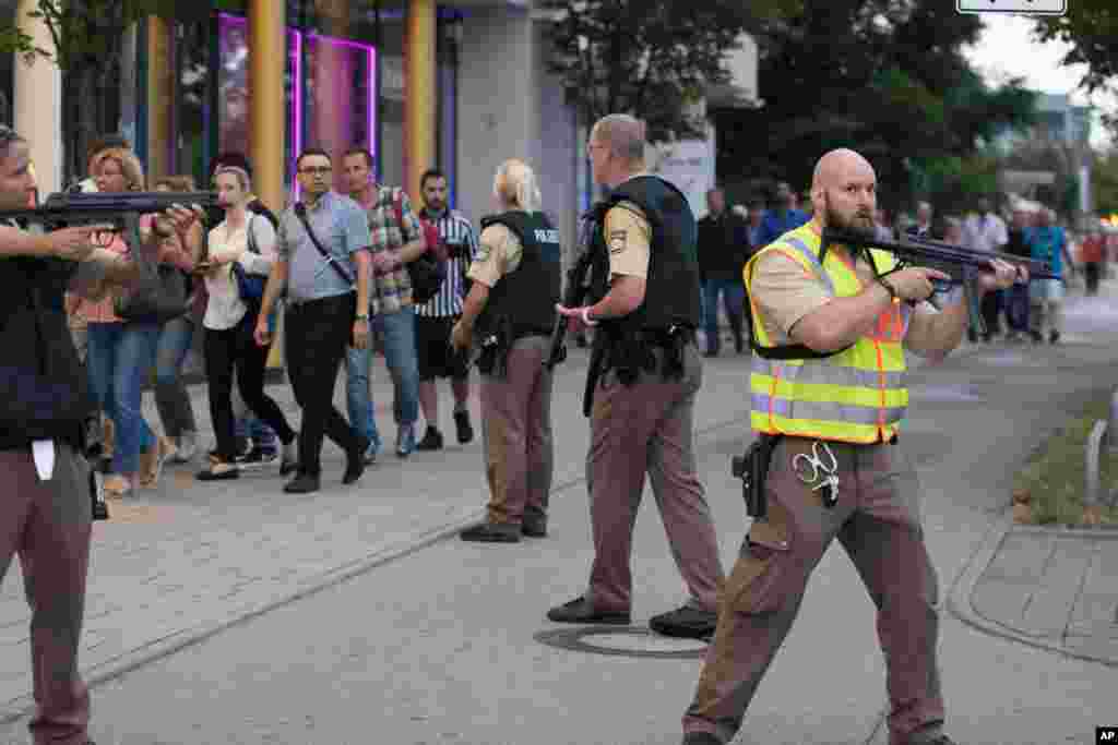 Police escort people who leave the Olympia mall in Munich, southern Germany, July 22, 2016 after shots were fired. 