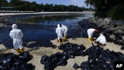 ​ພະ​ນັກ​ງານ​ອະ​ນາ​ໄມ​ນ້ຳ​ມັນ​ທີ່​ຮົ່ວ​ໄຫຼຢູ່​ຕາມ​ຫາດ​ຊາຍ​ຂອງ​ເກາະ ເຊັນ​ໂຕ​ຊາ, ສິງ​ກະ​ໂປ, 16 ມິ​ຖຸ​ນາ 2024