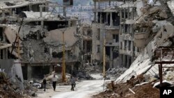 Residents walk through rubble with damaged electricity lines at the mountain resort town of Zabadani in the Damascus countryside, Syria, May 18, 2017.