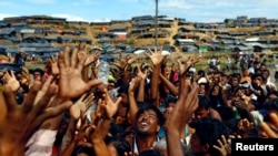 FILE - Rohingya refugees stretch their hands to receive aid distributed by local organizations at Balukhali makeshift refugee camp in Cox's Bazar, Bangladesh, Sept. 14, 2017.