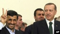 Iran's President Mahmoud Ahmadinejad flashes the V-sign for victory as Turkish Prime Minister Recep Tayyip Erdogan looks on after the Islamic republic inked a nuclear fuel swap deal in Tehran (File Photo - 17 May 2010)