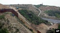 In this March 11, 2019 photo, construction crews replace a section of the primary wall separating San Diego, above right, and Tijuana, Mexico, below left, seen from Tijuana, Mexico.