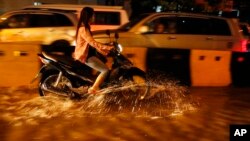 រូបឯកសារ៖ អ្នក​ធ្វើ​ដំណើរ​តាម​ម៉ូតូ​ម្នាក់​បើ​កាត់​ផ្លូវ​លិច​ទឹក​ដោយសារ​តែ​ភ្លៀង​ធ្លាក់​មួយ​មេឃ​ធំនៅ​ទីក្រុង​ភ្នំពេញ កាល​ពី​ថ្ងៃ​សុក្រ ទី៣១ ខែ​កក្កដា ឆ្នាំ២០១៥។ (AP/Heng Sinith)