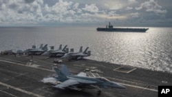 Jet tempur F/A-18E Super Hornet mendarat di dek kapal induk USS Ronald Reagan, sementara USS Nimitz melintas di Laut China Selatan, 6 Juli 2020.