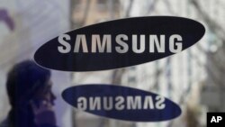 FILE - A man passes by the Samsung Electronics Co. logos at its headquarters in Seoul, South Korea.