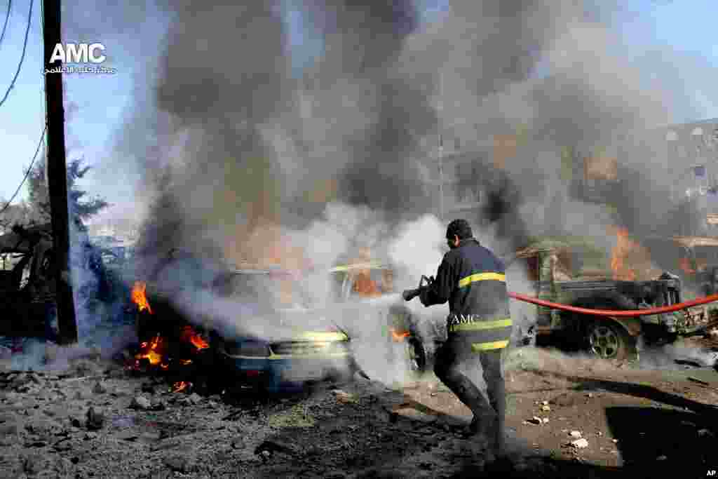 In this citizen journalism image, a firefighter hoses down burning vehicles after a Syrian air strike in Aleppo, Dec. 22, 2013.