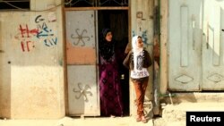 Warga berdiri di depan rumah mereka di Mosul Barat,Irak, 20 July 2017. 