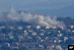 Asap mengepul dari sela-sela rumah di Kota Metula di perbatasan Israel utara yang terkena tembakan Hizbullah, terlihat dari sisi Kota Marjayoun, Lebanon, Lebanon, Sabtu, 22 Juni 2024. (Foto: AP)