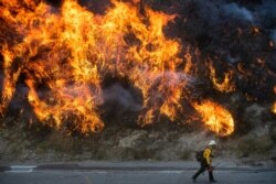 Flames from a backfire, lit by firefighters to stop the Saddleridge Fire from spreading, burn a hillside in Newhall, Calif., Oct. 11, 2019