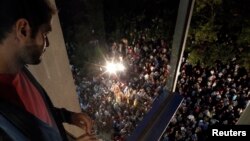 An employee looks at people gathering outside the Greek state television headquarters in Athens, June 11, 2013.