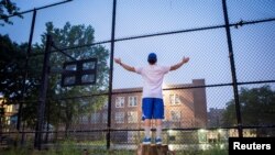 Emily Rodriguez says a prayer in front of Castle Hill Playground in the Bronx, ahead of the planned reopening of schools amid the coronavirus outbreak, in New York, Sept. 2, 2020.
