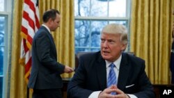 លោក​ប្រធានាធិបតី​ ដូណាល់ ត្រាំ អង្គុយនៅ​តុ​របស់​លោក​នៅ​សេត​វិមាន​ រង់​ចាំ​ប្រធាន​សេតវិមាន​ Reince Priebus ដែល​នៅ​ខាង​ក្រោយ​លោក ដើម្បី​ចុះ​ហត្ថលេខា​លើ​បទ​បញ្ជា​ចំនួន​៣​។