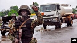 A Liberian soldier stops people at a security checkpoint set up to clamp down on people trying to travel to the capital from rural areas hard-hit by the Ebola virus, on the outskirts of Monrovia, Aug. 7, 2014.